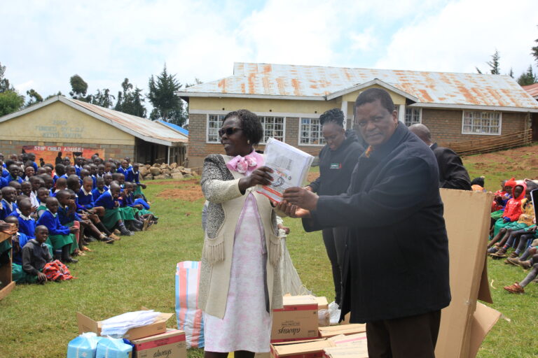 KIPPRA Board Chair Dr Benson Ateng’ hands over donations for the students